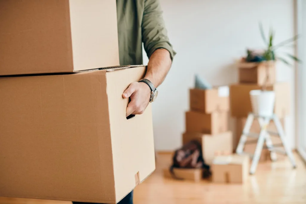 Closeup Man Carrying Cardboard Boxes While Relocating Into New Apartment